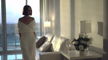 Bir bardak suyla güzel bir kadının 4K yaşam tarzı videosu. Çekici, kendine güvenen, beyaz iç çamaşırlı, esmer bir bayan. İç kısımda güzel güneş ışığı