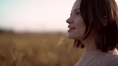 Genç ve güzel bir bayanın sonbahar manzarasında kuru çiçeklerle çekilmiş açık hava yavaş çekim videosu. Örgü süveter. Sıcak Sonbahar.