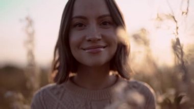 Genç ve güzel bir bayanın sonbahar manzarasında kuru çiçeklerle çekilmiş açık hava yavaş çekim videosu. Örgü süveter. Sıcak Sonbahar.