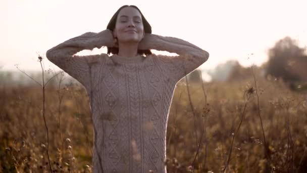 乾燥した花と秋の風景の中に若い美しい女性の屋外スローモーションビデオ ニットセーター 暖かい秋 — ストック動画