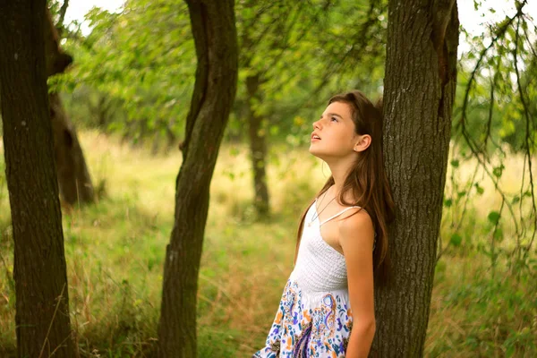 Ein Mädchen träumt im Sommer unter einem Baum Stockbild