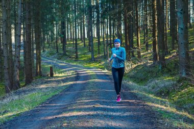 Genç kız bahar vakti ormanda koşuyor.