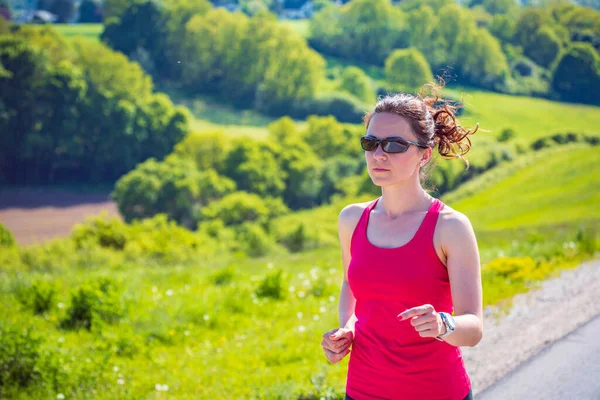 田舎をジョギングする若い女性が — ストック写真