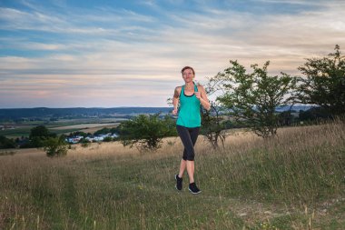 Kırsal alanın önünde koşan genç bir kadın.