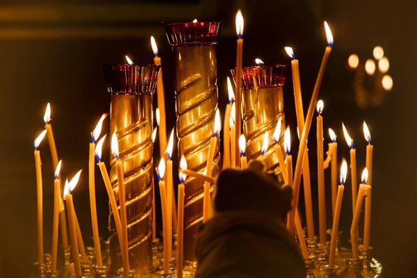 Woman hand lighting candles in the dark of a church — Stock Photo, Image