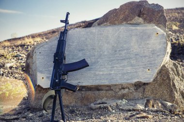 Granit döşeme, tepe ve arka planda mavi gökyüzü arka plan Kalaşnikof saldırı tüfeği yakın çekim