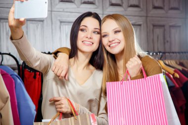 İki genç güzel kadın arkadaş alışveriş merkezi alışveriş torbaları bir sürü moda portre. Selfie yapma. Gülümseyen ve mutlu alışveriş sonra.
