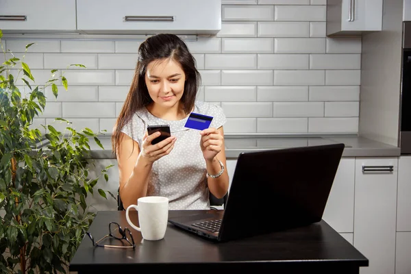 Genç kadının bir kredi kartı ve telefon kullanarak bir online alış-veriş yapması