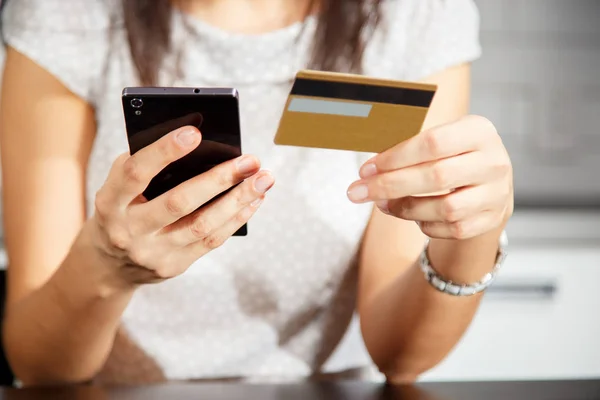 Online ödeme, kredi kartı tutan ve online alışveriş için akıllı telefon kullanan kadınların elleri