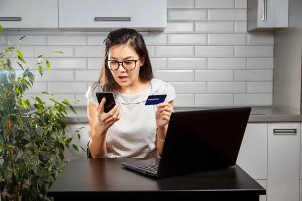 Jonge vrouw bang en holding een credit card en uw smartphone — Stockfoto