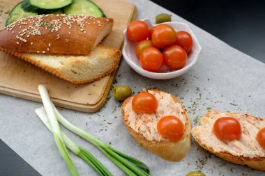 Kiraz domates ve yeşil zeytin, krem peynir, sağlıklı kahvaltı veya aperatif huysuz baget dilimlerle üstten görünüm ahşap oyun tahtası