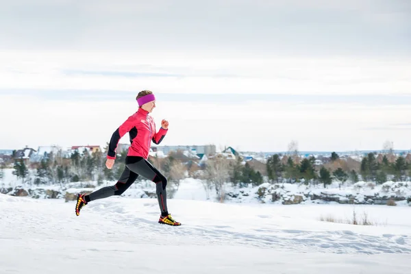 Narciarstwo biegowe ćwiczeń. Biegacza jogging w śniegu. Młoda kobieta model fitness, uruchomiona w parku miejskim. — Zdjęcie stockowe
