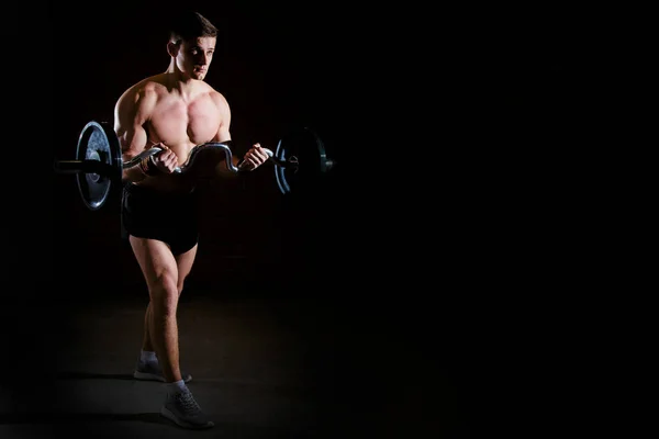 Retrato de un hombre musculoso con barra de pesas en el gimnasio. Brutal culturista atlético hombre con abdominales perfectos, hombros, bíceps, tríceps y pecho. Entrenamiento de barras de levantamiento de pesas —  Fotos de Stock
