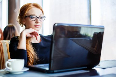 Kafede dizüstü bilgisayar kullanan bir kadın..