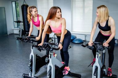 Üç güzel genç kadın spor bisiklet üzerinde çalışma dışarı