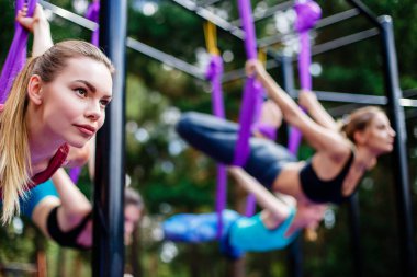 Bir grup genç kadını parkta egzersiz Anti-yerçekimi yoga gerçekleştirmek