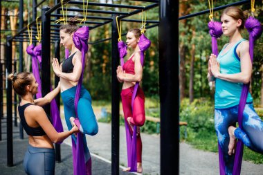 Bir grup genç kadını bir şehir parkta bir hava yoga sınıfında bir koç ya da öğretmen ile nişanlı