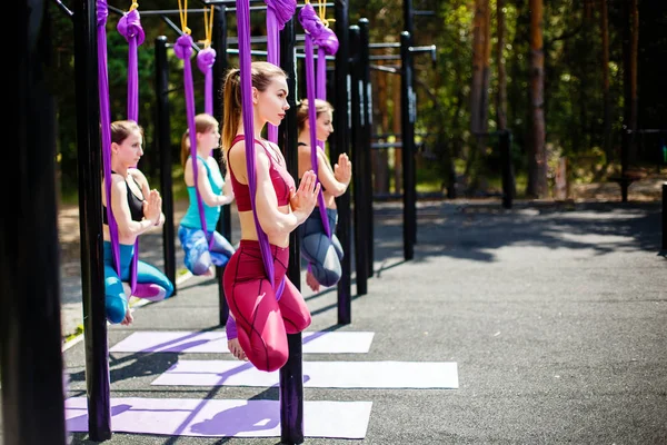 Un grupo de mujeres jóvenes practicando yoga aéreo en el Parque al aire libre — Foto de Stock