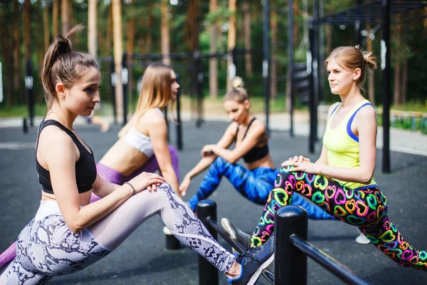Jóvenes atletas femeninas estirándose antes de correr en el parque — Foto de Stock