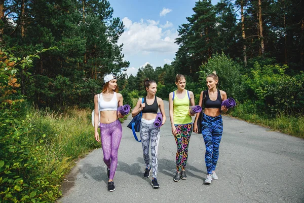 The company of young attractive women friends with sports equipment going for a workout in the Park