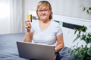 Yaşlılar ve modern teknoloji kavramı. Bir 50s portresi Olgun kadın el kredi kartı, online internet ödeme evde kullanma tutarak. Kapalı üst düzey insanların yaşam tarzı.