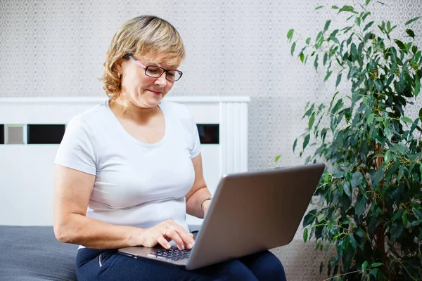 Gülümseyen kadın kıdemli laptop evde çalışma