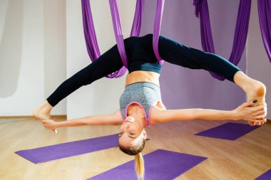 Genç kadının germe ve sicim yapması. Hava yoga egzersiz veya antigravity yoga kapalı. Fitness, stretch, denge, egzersiz ve sağlıklı yaşam tarzı. Hamak kullanan kadın.