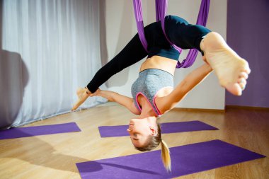 Genç kadının germe ve sicim yapması. Hava yoga egzersiz veya antigravity yoga kapalı. Fitness, stretch, denge, egzersiz ve sağlıklı yaşam tarzı. Hamak kullanan kadın.