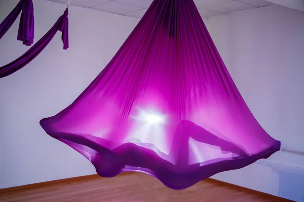 Hamak kullanan bir kadın silueti. Genç kadın hava yoga egzersiz veya antigravity yoga kapalı yapıyor. Uçan, fitness, stretch, denge, egzersiz ve sağlıklı yaşam tarzı.