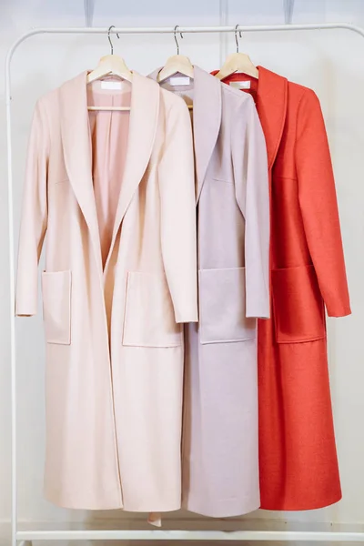 Trzy kobiety moda płaszcze na wieszakach w sklepie — Zdjęcie stockowe