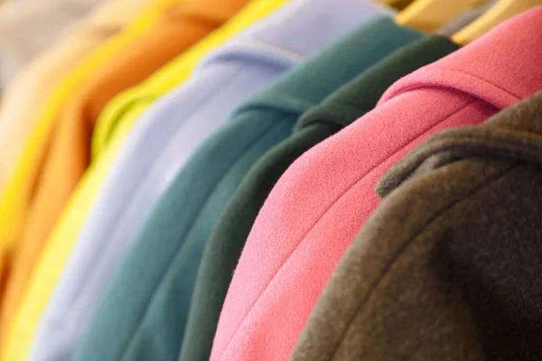 Kolory tęczy. Wybór modne płaszcze na wieszakach w sklepie — Zdjęcie stockowe