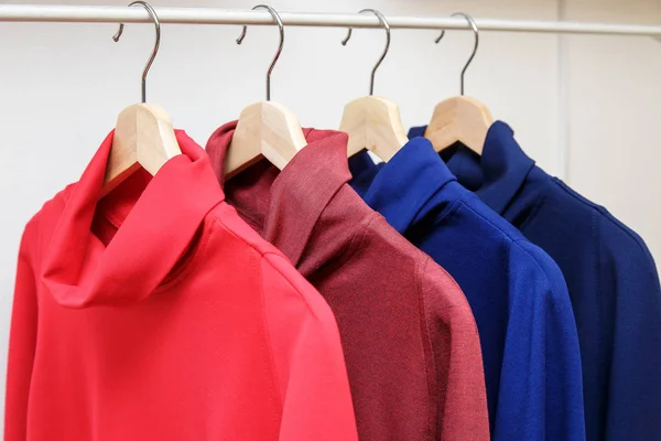 Радужные цвета. Выбор повседневной одежды на деревянных вешалках в магазине — стоковое фото