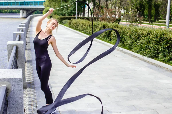 Fashionable slim girl on the street with a gymnastics ribbon — Stock Photo, Image