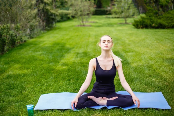 Junge Frau in Lotus-Pose im Park — Stockfoto