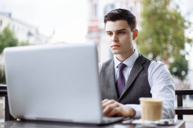 Takım elbise ve modern dizüstü açık havada, kullanma yakışıklı işadamı başarılı yönetici kafede break ve Internet arama bilgilerinde kendi dizüstü bilgisayarında sırasında çalışma