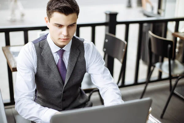 Красивый бизнесмен в костюме и с современным ноутбуком на открытом воздухе, успешный менеджер, работающий в кафе во время перерыва и поиск информации в Интернете на своем ноутбуке — стоковое фото