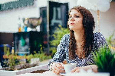 Genç çekici kız bir şehir kafede kahve içecekler