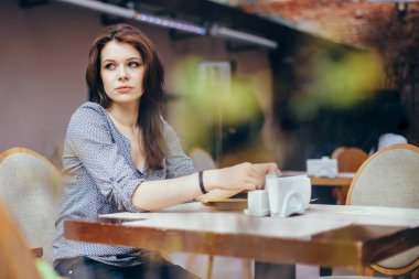 Dalgın bir kadın garson modern café iç beklentisiyle bir şey hakkında rüyalar. Ön plan ile çekim.