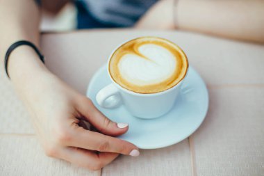 Bir kafede bir kapuçino Kupası ile eller