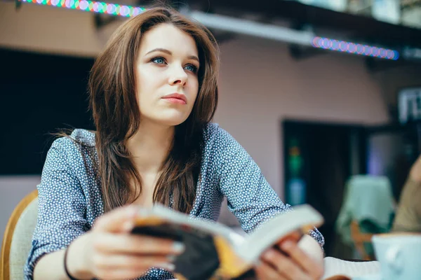 Genç kadın kahve dükkanında bir kitap okumak