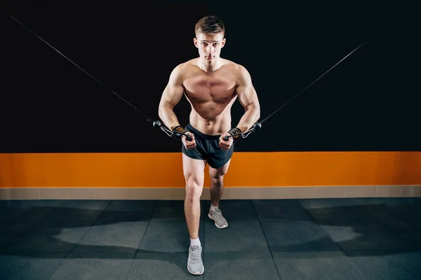 Молодой человек делает ручную резку симулятора в спортзале. Упражнения для мышц груди. Кроссовер . — стоковое фото