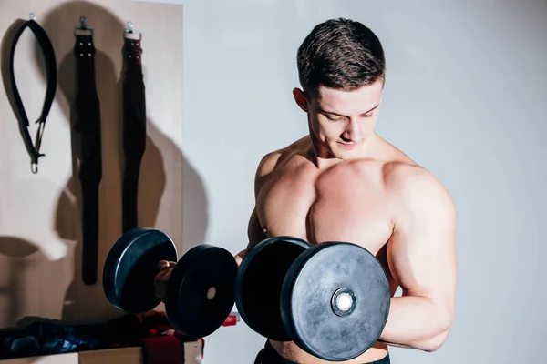 Крупный план сильного спортсмена, тренирующегося накачивать мышцы гантелями — стоковое фото