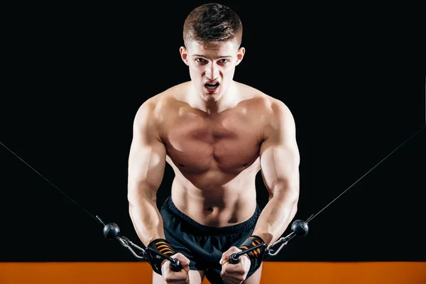 Молодой человек делает ручную резку симулятора в спортзале. Упражнения для мышц груди. Кроссовер . — стоковое фото