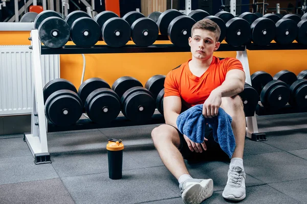 Biraz ara. Spor giyim yakışıklı genç adam eğitim salonunda, oturup pencereden bakmak sonra sakin ol. Fitness Center'da seksi adam