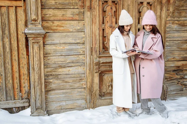 두 아름 다운 여자를 입고 따뜻한 겨울 옷 잡지 읽고 야외 — 스톡 사진