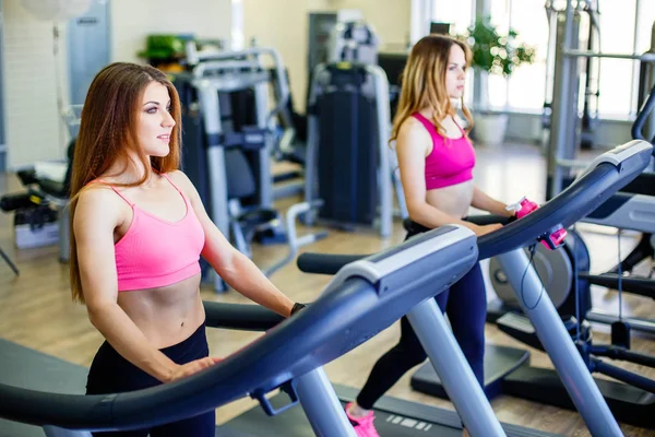 Junge sportliche Frauen laufen auf Laufbändern im Fitnessstudio — Stockfoto