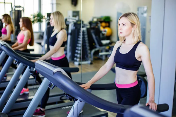 Correr en la cinta de correr en el gimnasio o club de fitness - grupo de mujeres haciendo ejercicios de cardio — Foto de Stock