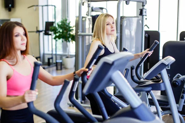 Zusammenlaufen. Seitenansicht von jungen schönen Frauen, die wegschauen, während sie im Fitnessstudio auf dem Laufband laufen — Stockfoto