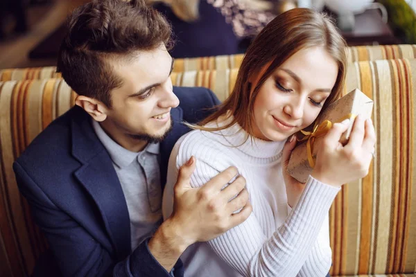 De jonge man geeft een cadeau aan zijn geliefde vrouw bij de koffieshop - het concept van geluk, relaties en viering — Stockfoto