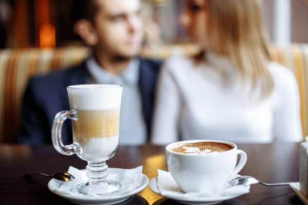 Coffee drinks on a table with a pair of lovers in the background